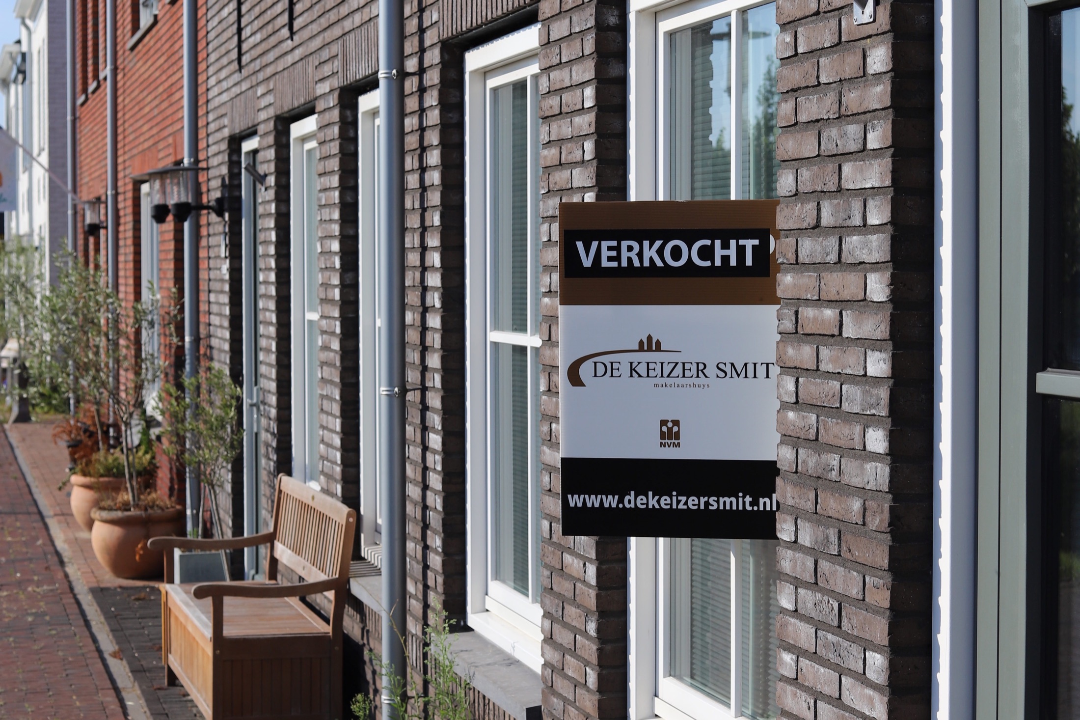 Rij woningen met een verkocht-bord aan een gevel