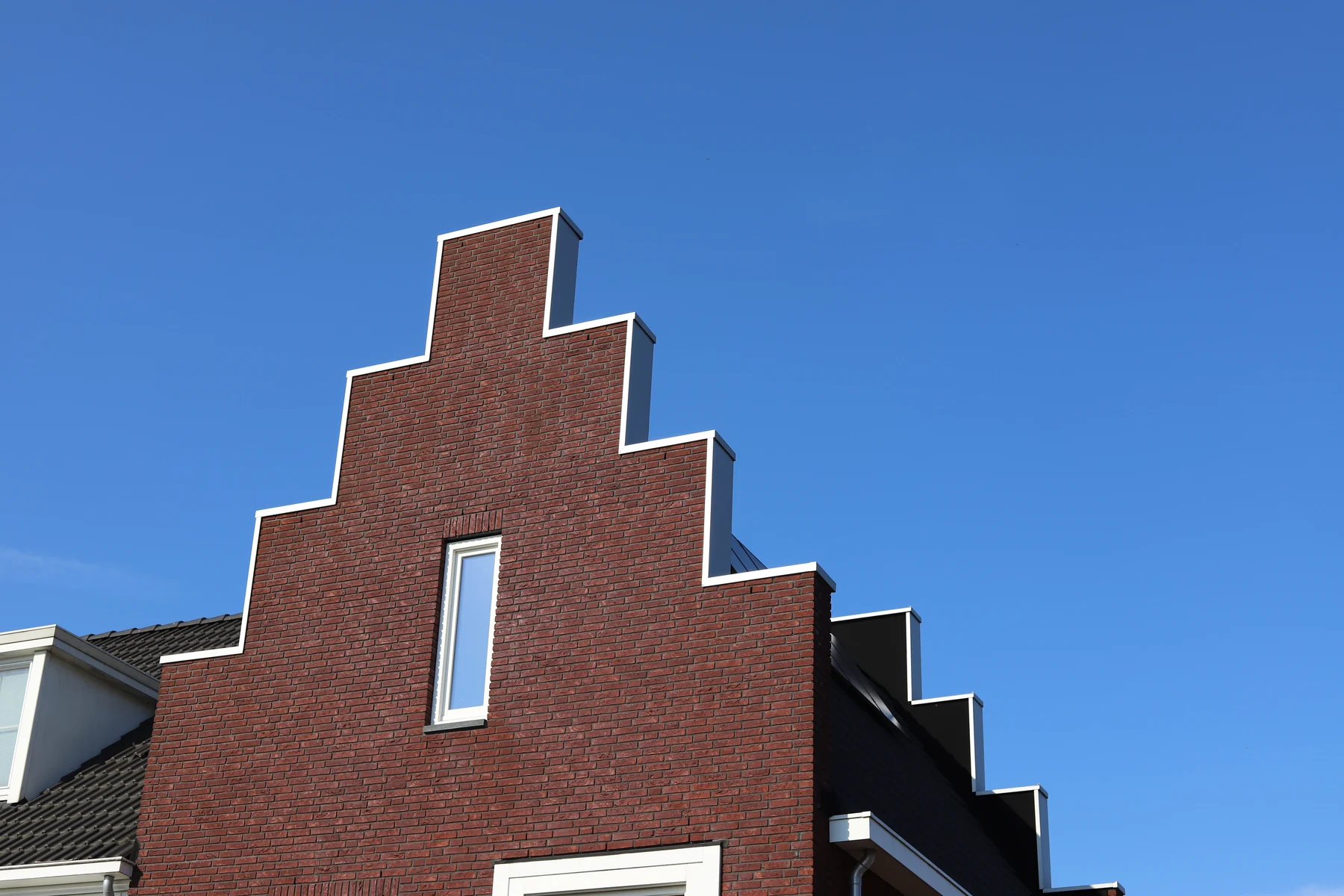 Bakstenen trapgevel tegen een blauwe lucht in Hoef en Haag